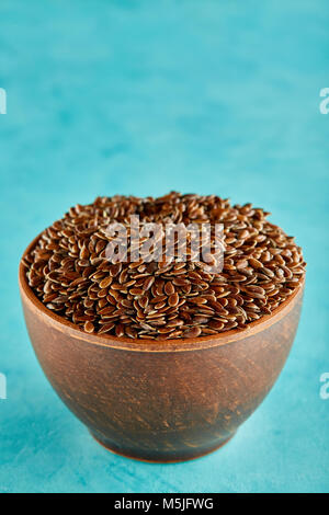 Narural raw Leinsamen in einem keramischen Ton Schüssel auf blauem Hintergrund isoliert, close-up. Nützlich und Ernährung Ölsaaten für das tägliche Kochen. Gesunde eatin Stockfoto