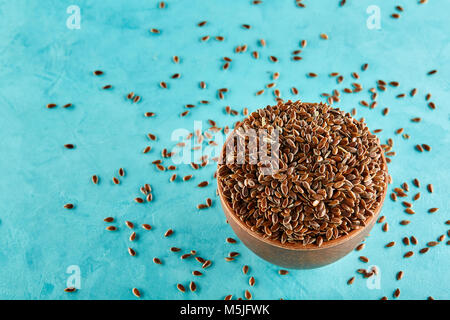 Narural raw Leinsamen in einem keramischen Ton Schüssel auf blauem Hintergrund isoliert, close-up. Nützlich und Ernährung Ölsaaten für das tägliche Kochen. Gesunde eatin Stockfoto