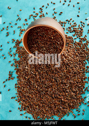 Narural raw Leinsamen in einem keramischen Ton Schüssel auf blauem Hintergrund isoliert, close-up. Nützlich und Ernährung Ölsaaten für das tägliche Kochen. Gesunde eatin Stockfoto