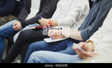 Eine Menge Leute sitzen in der Halle in Vortrag und Notizen - Teilnehmer schreiben in ihre Notebooks Stockfoto