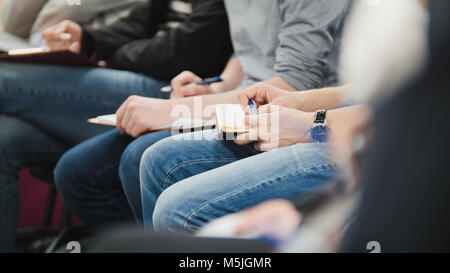 Die Leute an der Darstellung n Business Halle in Vortrag und Notizen - Leute schreiben in ihre Notebooks Stockfoto