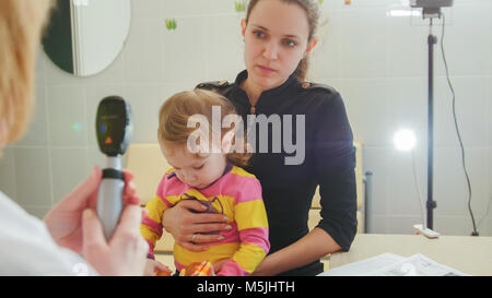 Ophthalmologie - Arzt Konsultationen mit der Mutter des Mädchens über Sehvermögen von kleines Mädchen - Child's Healthcare Stockfoto