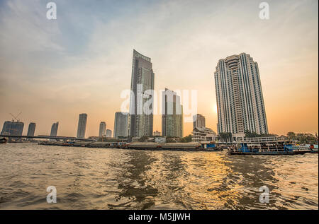 BANGKOK, THAILAND, MÄRZ 02, 2017 - Chao Praya Fluss in Bangkok, Gebäude und Schiffe bei Sonnenuntergang Stockfoto