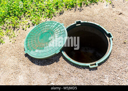 Ungesicherte Abwasserkanal Mannlöcher des ländlichen septischen Tank mit grünem Kunststoff Abdeckung geöffnet Stockfoto