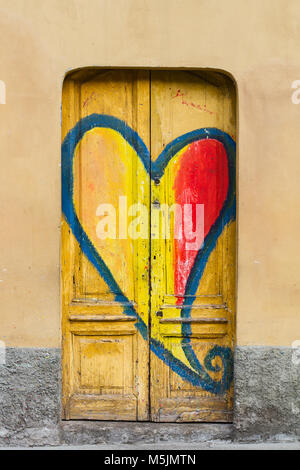 Vertikale Frontansicht Detail des Blauen graffiti Form Abbildung auf dem gelben Gebäude vintage Tür Stockfoto