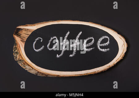 Ein Namensschild aus einer Birke Board mit dem Text von Kaffee auf einem schwarzen Brett. Ansicht von oben. Stockfoto