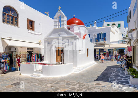 MYKONOS, Griechenland - 23. Mai 2017: Ein Blick auf die typische griechische Kirche Gebäude auf Platz mit Geschäften in der Stadt Mykonos. Die Kykladen, Griechenland Stockfoto