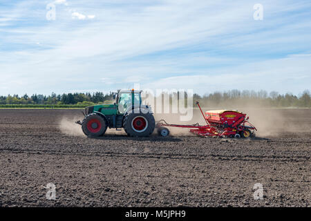 Traktor mit Sämaschine arbeitet ein Feld im Frühling, Län, Dänemark Stockfoto