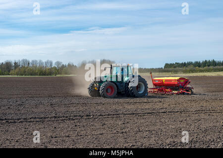 Traktor mit Sämaschine arbeitet ein Feld im Frühling, Län, Dänemark Stockfoto