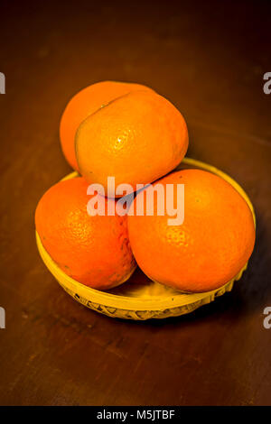 Nahaufnahme von frischen reifen Orangen, Citrus aurantium in einem Korb auf Holz- Oberfläche. Stockfoto