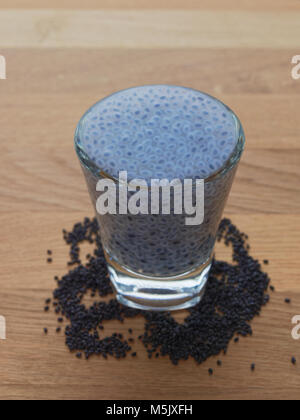 Basilikum oder Sabja Samen in shot Glas mit getrockneten Samen auf hölzernen Hintergrund schwoll Stockfoto