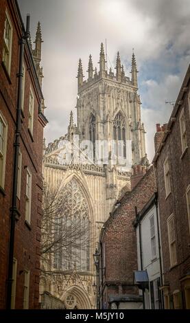 Der Turm des York Minster betrachtet aus einer Seitenstraße mit Häusern zu beiden Seiten. Stockfoto