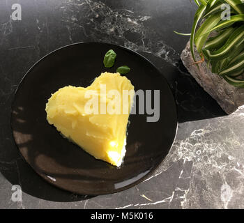 Kartoffelpüree in Herzform mit Basilikum als Dekoration Stockfoto