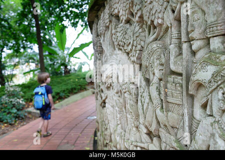 Junge zu Fuß mit einem Rucksack an der Wand Relief zeigt die Geschichte von Singapur, Fort Canning Park, Singapur Stockfoto