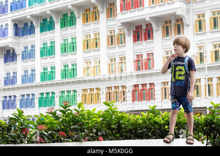 Junge süße blonde Western Junge stand vor der er Glimmer Gebäude, Singapur Stockfoto