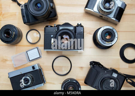 Mischen von alten Kameras auf hölzernen Schreibtisch-Hintergrund. Stockfoto