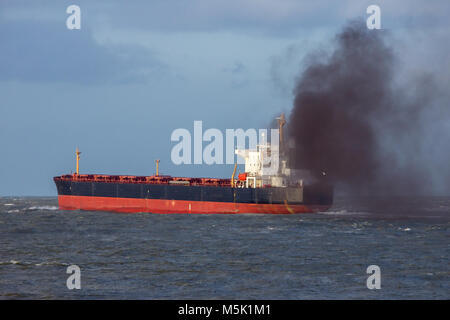 Industrielle Luftverschmutzung verursacht cargo Schiff verlässt den Hafen von Rotterdam. Stockfoto