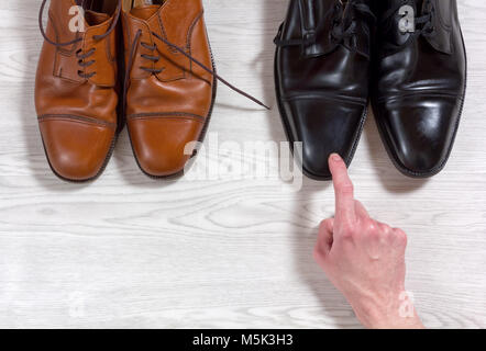 Männliche hand eine der beiden Schuhe vor ihm auswählen Stockfoto