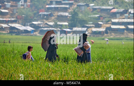 Menschen tragen ein tarp, Decken und andere Gegenstände, die Sie aus einer Beihilfe in einem Reisfeld in der Jamtoli Flüchtlingslager in Bangladesch erhalten. Stockfoto