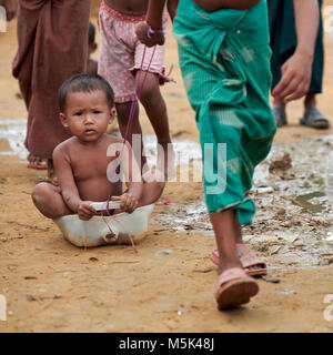 Ein Rohingya Flüchtlinge Kind hält sich fest, wenn ein anderes Kind sie entlang der Schmutz der Straße in der weitläufigen Kutupalong Flüchtlingslager in Bangladesch zieht. Stockfoto