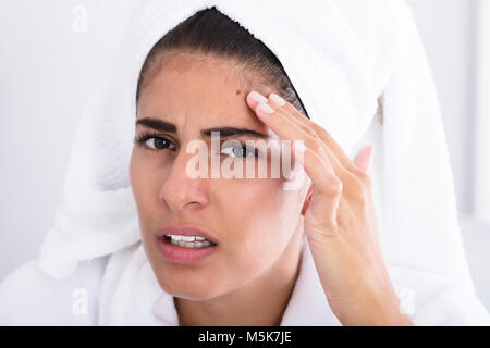 Nahaufnahme der jungen Frau auf Pickel auf der Stirn und Zusammendrücken. Stockfoto