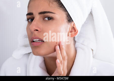 Nahaufnahme der jungen Frau auf Pickel auf der Stirn und Zusammendrücken. Stockfoto