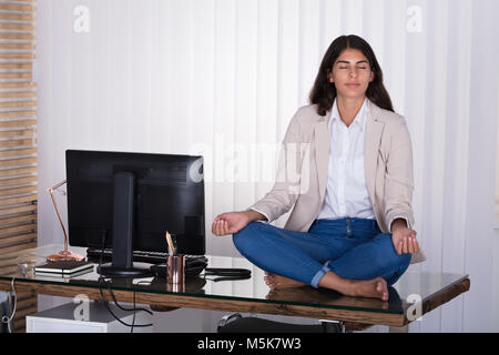 Junge Büro Arbeiterin meditieren Auf dem Schreibtisch im Büro Stockfoto
