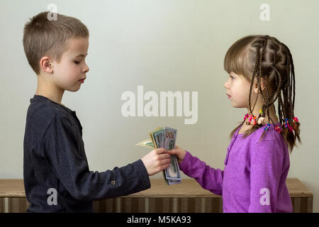 Zwei kleine Kinder, Junge und Mädchen spielen mit Dollar Geld Stockfoto