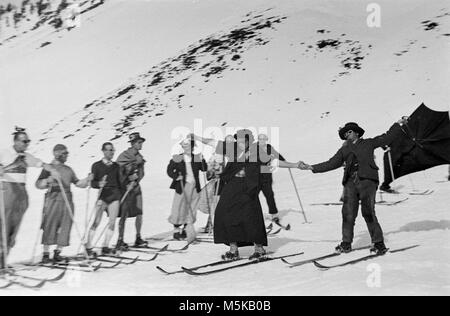 Skifahren in der Schweiz im Jahr 1937. Eine Gruppe von Skifahrern in Fancy Dress auf den Skipisten. Stockfoto