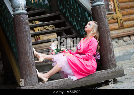 Russland, Moskau, izmaylovsky Park, 27. August 2017. Internationale Foto Festival. Eine wunderschöne Blondine mit einem Blumenstrauß auf den Stufen sitzt. Das Mädchen träumt von Stockfoto