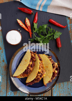 Chili con Carne in Schüssel mit Chips, Sauce und Gemüse, auf weiß