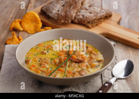 Chanterelle Pilzsuppe und Roggen Brot auf einem rustikalen Tisch Stockfoto