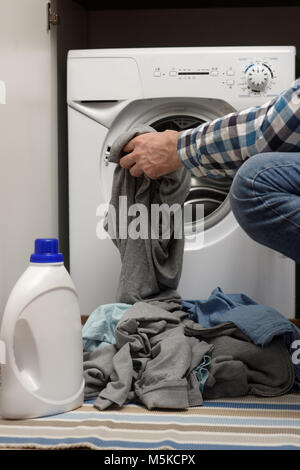 Mann, schmutzige Wäsche in die Waschmaschine geöffnet Stockfoto