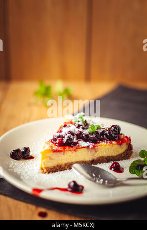 Schöne traditionelle italienische Käsekuchen mit roten Früchten, Minze, und Puderzucker auf hölzernen Hintergrund, selektiver Fokus Stockfoto