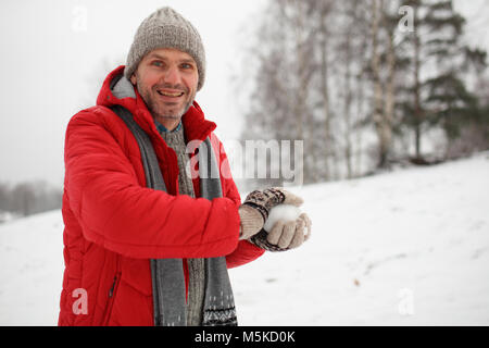 Reifer Mann das schneeball während Schneeballschlacht Stockfoto