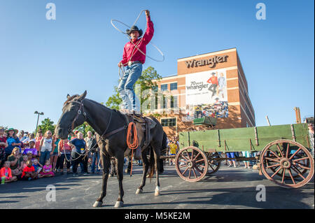 Mann in Cowboy Hut steht auf Pferd während Vorformen lasso Trick vor Wrangler Gebäude, Greensboro, North Carolina. Stockfoto