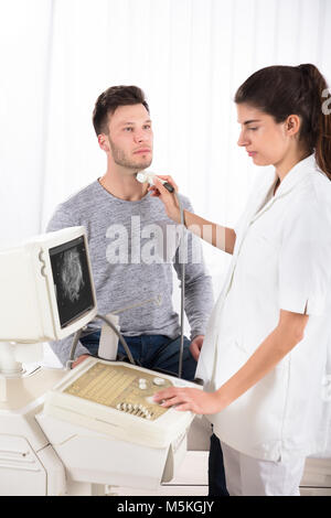 Junger Mann, Ultraschall am Hals der jungen Ärztin in der Klinik Stockfoto