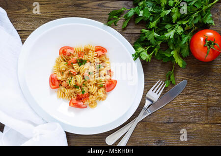 Warmer Salat mit Meeresfrüchten in einer weißen Schüssel auf einem hölzernen Hintergrund. Pasta Radiatori mit Krebsen, Garnelen, Tomaten, Kräuter und cremige Knoblauchsauce. Stockfoto