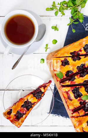 Eine köstliche hausgemachte Kuchen mit Beeren, in Stücke schneiden und eine Tasse duftenden Kaffee. Ansicht von oben. Traditionelle amerikanische Gericht für Independence Day. Stockfoto