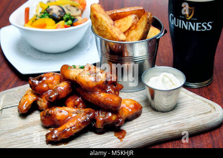 Chicken Wings warf in bbq und Sweet Chili Sauce mit Blue Cheese dip, Chips und ein Pint Guinness, Doheny & Nesbitt Pub, Dublin, Irland Stockfoto