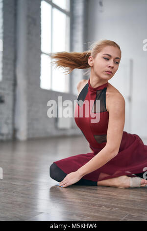 Schöne Mädchen Tänzerin sitzt auf dem Boden in der Halle Stockfoto