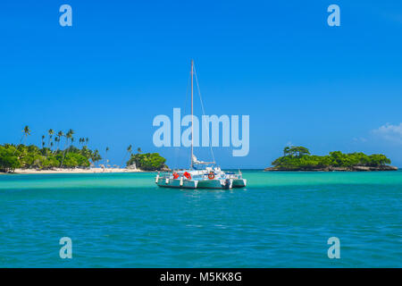 Katamaran vor einem wunderschönen Insel, weißer Strand, blauer Himmel und türkisfarbenem Wasser Stockfoto