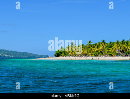 Schöner Strand mit Palmen, blauer Himmel und türkisfarbenem Wasser, einige Touristen Spaß haben, entspannen und schwimmen im Meer, Karibik Stockfoto