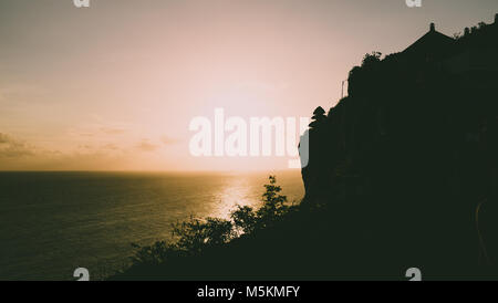 Der Sonnenuntergang über dem Meer von einem Tempel auf den Klippen in Uluwatu, Bali gesehen Stockfoto