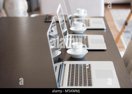 Mehrere Computer mit Kaffee in einer Büroumgebung Seite der Konferenztisch. Stockfoto