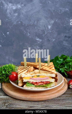 Club-Sandwiches mit knusprigem Toast, Wurst, Käse, Tomaten, Grüns. Traditionelle amerikanische Snack. Stockfoto