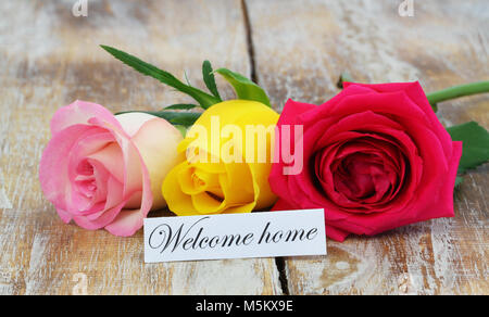 Home Karte mit drei bunten Rosen auf Holz- oberfläche Willkommen Stockfoto