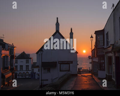 Die Sonne zwischen zwei Gebäuden in der Küstenstadt Lyme Regis. Stockfoto