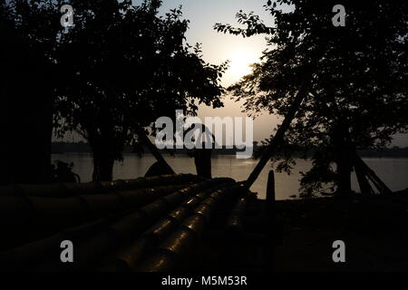 Kutighat, Kolkata, Indien. 24. Februar 2018. Riverine Handel auf Bambus. Migrant Bihari laborors hochladen Bambus für Lieferung auf die Stadt bei Sonnenuntergang auf Hoogly Bank. Traditionell die Bambusse sind Wasser im Fluss Hoogly aus pretzfeld oder innere Westbengalen transportiert. Credit: Rupa Ghosh/Alamy Leben Nachrichten. Stockfoto