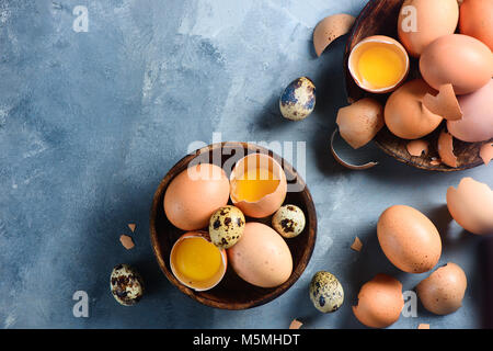 Kochen mit rohen Eiern Hintergrund. Wachtel und braunen huhn eier auf einem Holz- Gericht. Moderne Ostern Konzept mit kopieren. Stockfoto